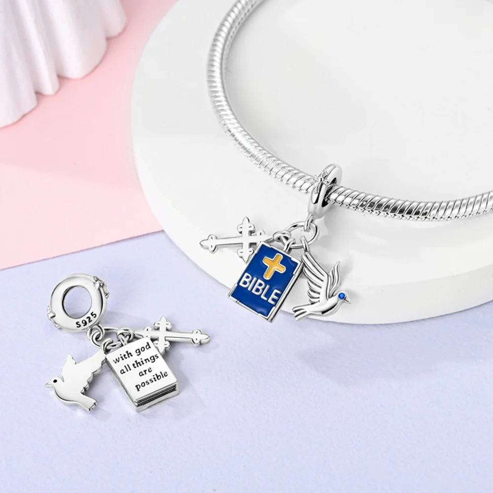 Silver bracelet with religious-themed charms on a light pink and white background